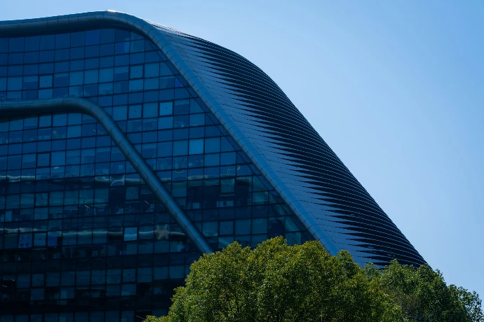 Modern glass building with wavy facade and trees
